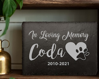 May include: Black slate memorial plaque with the text "In Loving Memory Coda 2010-2021" and a white paw print inside a heart.
