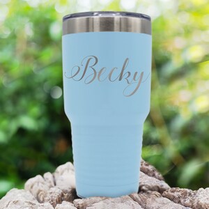May include: A light blue stainless steel tumbler with a silver inscription that reads "Becky".