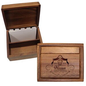 Pu&ograve; includere: Una scatola per ricette rettangolare in legno con coperchio incernierato. Il coperchio presenta un design inciso con un cappello da chef, la lettera W, il testo SINCE 2016, Warner e FAMILY RECIPES. L'interno aperto contiene schede bianche con linguette.