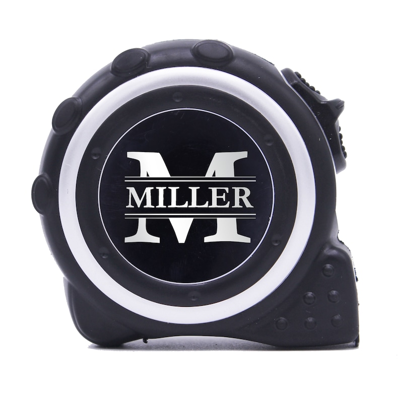May include: Black and silver tape measure with the name "MILLER" in white. The tape measure is black with a silver rim and a black center. The tape measure is a construction tool.