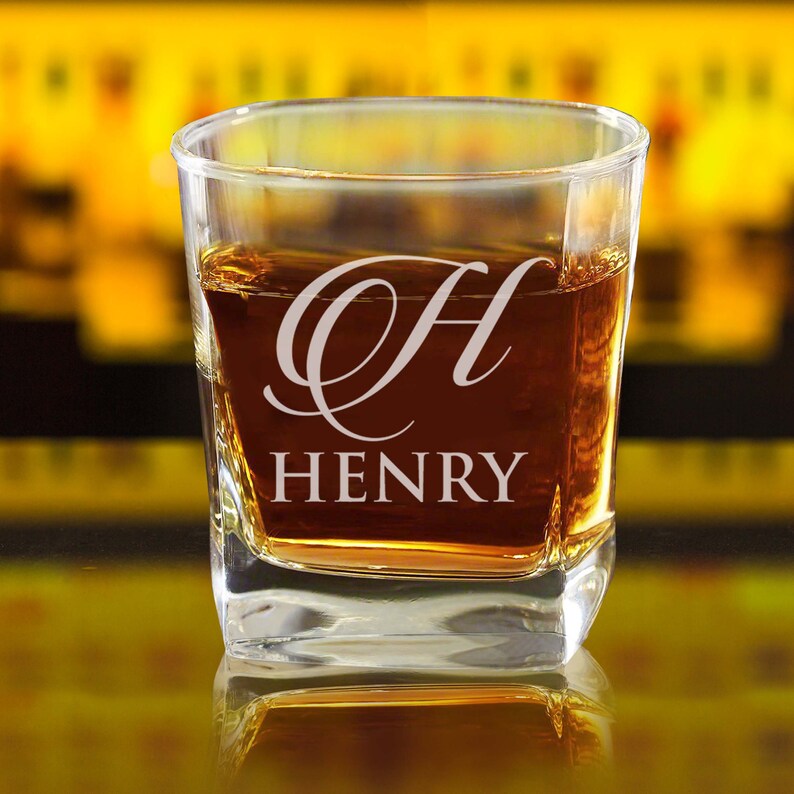Pode incluir: Um copo de u&iacute;sque de vidro transparente com uma inscri&ccedil;&atilde;o personalizada. O copo est&aacute; cheio de l&iacute;quido &acirc;mbar e a inscri&ccedil;&atilde;o diz "H HENRY".
