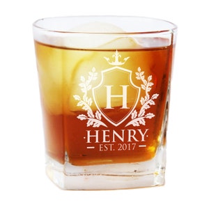 May include: A clear glass rocks glass with a white engraved design. The design features a shield with a crown, the letter H, and the words "Henry Est. 2017".