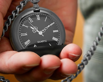 May include: A black pocket watch with Roman numeral markings on the face and a black chain. The watch face says "QUARTZ".