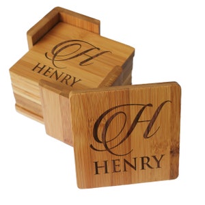 May include: A stack of square bamboo coasters with a matching holder. Each coaster features a laser-engraved design consisting of a large cursive letter H positioned above the name HENRY in a bold, capitalized, sans-serif typeface.