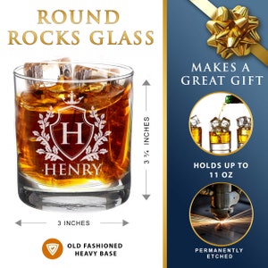 May include: A personalized round rocks glass with a heavy base. The glass is etched with a crest featuring the letter "H" and the name "HENRY". The glass is 3 inches wide and 3 3/4 inches tall. It holds up to 11 ounces.