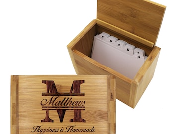 May include: A bamboo recipe box with a hinged lid, open to reveal white index cards. The box features the name "Matthews" and the phrase "Happiness is Homemade" engraved on the front.