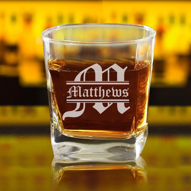 May include: A clear glass rocks glass with a personalized etched design. The glass features a large initial "M" with the name "Matthews" etched below it.