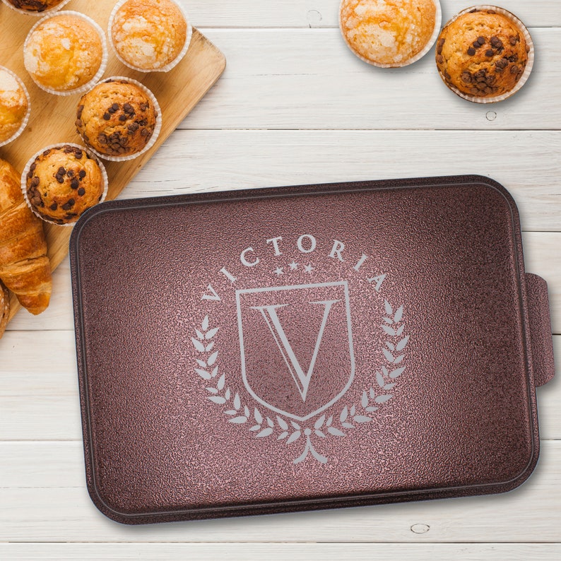 May include: A brown baking sheet with a raised edge and a silver embossed design that says "VICTORIA" with a crest and a "V" inside.