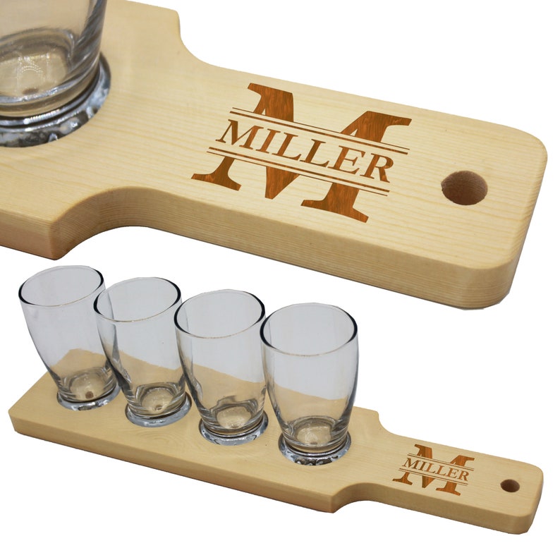 May include: Two wooden beer flight boards with clear glasses. One board holds a single large glass, the other holds four smaller glasses. Both boards are engraved with the name "MILLER" and the letter "M".