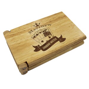 Puede incluir: Un tablero de cribbage de madera con una inscripci&oacute;n personalizada que dice "MATTHEW W" y un dise&ntilde;o de cartas de juego con una pancarta que dice "CRIBBAGE MASTER".