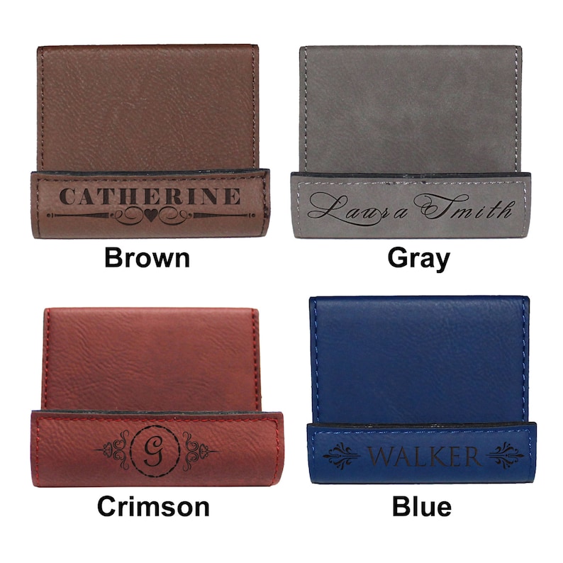 May include: Four leather business card holders in different colors: brown, gray, crimson, and blue. Each holder has a different engraved design. The brown holder has the name "Catherine" engraved on it. The gray holder has the name "Laura Smith" engraved on it. The crimson holder has the letter "G" engraved on it. The blue holder has the word "WALKER" engraved on it.