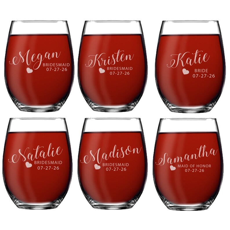 May include: Six clear stemless wine glasses filled with red liquid. Each glass features white script text with names Megan, Kristen, Katie, Natalie, Madison, and Samantha, along with titles like BRIDESMAID, BRIDE, or MAID OF HONOR and the date 07-27-26.
