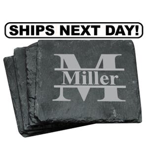 May include: A stack of square black slate coasters with rough, natural edges. The top coaster features a large, light gray engraved letter M with the name Miller centered horizontally across the letter. Above the coasters is the text SHIPS NEXT DAY!