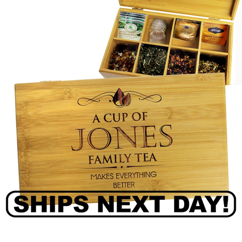 K&ouml;nnte beinhalten: Eine rechteckige Tee-Aufbewahrungsbox aus Bambus mit Klappdeckel. Der Deckel ist mit dem lasergravierten Text A CUP OF JONES FAMILY TEA MAKES EVERYTHING BETTER versehen. Das offene Innere der Box enth&auml;lt acht F&auml;cher mit verschiedenen Teebeuteln.