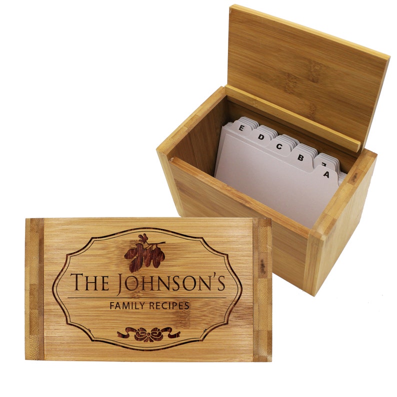 Pu&ograve; includere: Una scatola per ricette in bamb&ugrave; marrone chiaro con coperchio incernierato che presenta il testo inciso al laser THE JOHNSON'S FAMILY RECIPES all'interno di un bordo decorativo. La scatola aperta contiene schede bianche con linguette alfabetiche A, B, C, D ed E.