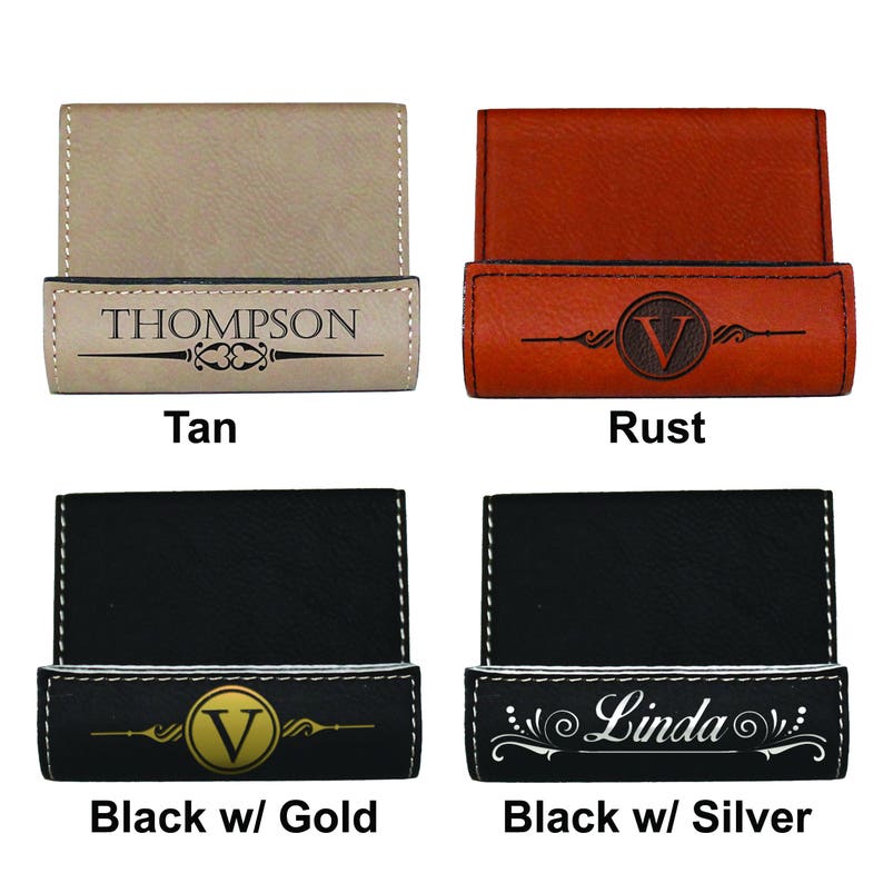 May include: Four different colored leather business card holders with personalized engravings. The holders are tan, rust, black with gold, and black with silver. The engravings include a name, initial, and decorative design.