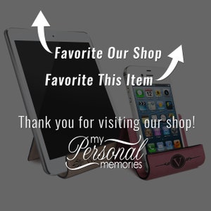 May include: Two cell phone stands, one for a tablet and one for a smartphone, both made of brown leather with a pink leather insert. The tablet stand has a white tablet in it and the smartphone stand has a black smartphone in it. The text "my Personal memories" is on the tablet stand.