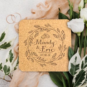 May include: A cork coaster with a brown floral wreath design, the names Mandy & Eric, and the date 07-30-24 engraved in the center.