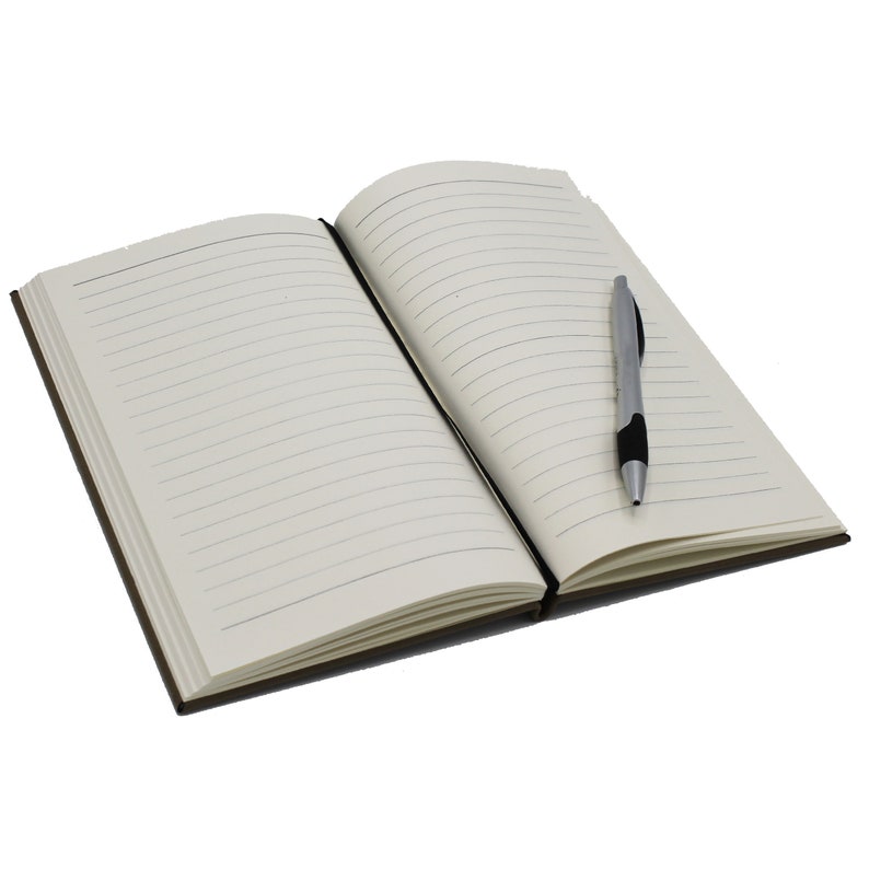 Puede incluir: Un cuaderno abierto, con l&iacute;neas, con lomo negro y cubierta marr&oacute;n. Un bol&iacute;grafo plateado y negro descansa sobre la p&aacute;gina derecha. Las p&aacute;ginas son de color crema con l&iacute;neas horizontales.