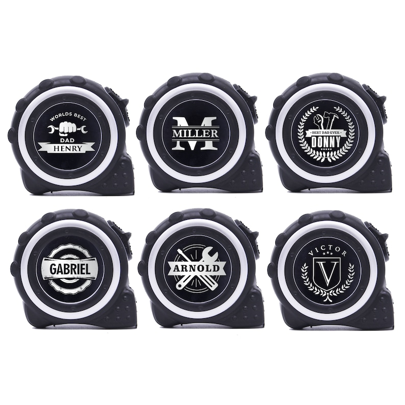May include: Six black and white personalized tape measures. Each tape measure has a white circular face with a different name or text, such as "Worlds Best Dad Henry" or "Miller". The tape measures are for construction or DIY projects.