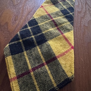 May include: A yellow, black, and burgundy plaid necktie. The tie is made of a textured fabric and features a classic plaid pattern. The tie is angled, showing its shape and design.