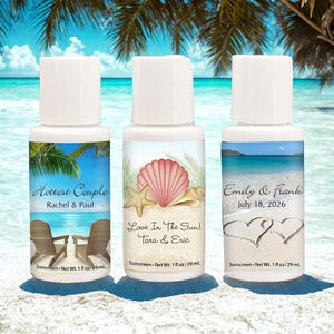 May include: Three white sunscreen bottles with personalized labels. One label reads "Hottest Couple" with names and beach chairs. Another says "Love In The Sun!" with a seashell design. The third says "Emily & Frank" with a date and heart design. Each bottle contains 1 fl oz / 29 mL.