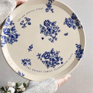 May include: A round cream-colored ceramic plate featuring blue floral patterns, a small blue heart, and the text "YOU ARE SPECIAL TODAY" and "THE KNIGHT FAMILY CELEBRATION PLATE" printed in black lettering along the curved edges.