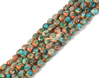 Può includere: Una collana di perle di diaspro turchese, marrone e arancio. Le perle sono sfaccettate e hanno una forma naturale irregolare. Le perle sono infilate su un filo elastico trasparente.