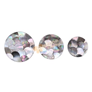 Può includere: Tre piatti decorativi rotondi realizzati in madreperla iridescente. I piatti sono di dimensioni diverse e presentano un motivo di cerchi sovrapposti.