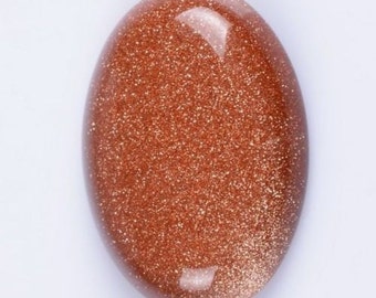 Puede incluir: Un cabujón de piedra de sol pulido, de forma ovalada y lisa, de color marrón rojizo y una textura brillante y brillante.