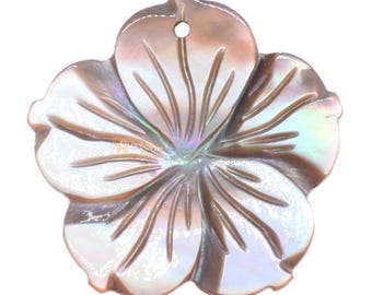 May include: A large, iridescent, mother-of-pearl flower pendant with a hole at the top for hanging. The flower is carved with a detailed design and has a light brown color.