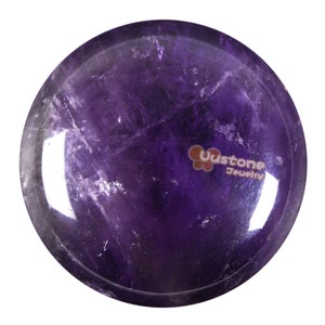 May include: A round, polished amethyst stone with a deep purple colour. The stone has a smooth, glossy finish and is perfect for meditation or crystal healing.