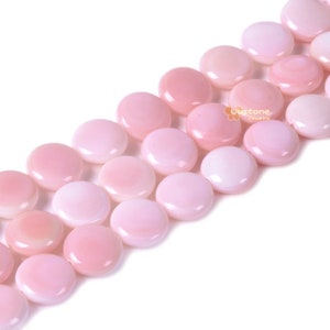 May include: A strand of pink shell beads, each bead is round and flat, with a smooth, polished surface.