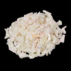 May include: A pile of white and pink iridescent shell pieces. The shell pieces are irregular in shape and size.