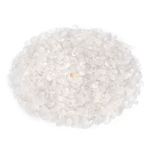 May include: A collection of small, clear quartz crystal chips. The crystals are translucent and irregularly shaped, creating a textured appearance. The chips are scattered, with a bright light illuminating them. Ideal for crafts or spiritual practices.