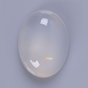 May include: A smooth, oval-shaped, white gemstone. The gemstone is translucent and has a slight sheen.