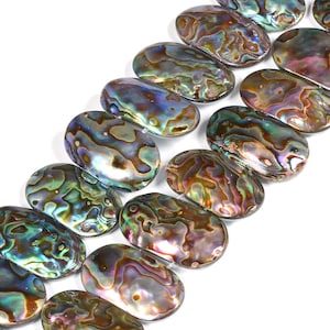 Könnte beinhalten: Nahaufnahme von ovalen Abalone-Muschelkernperlen mit schillernden Farben in Grün, Blau, Lila und Braun. Die polierten Perlen sind in Reihen angeordnet und eignen sich ideal für Schmuck oder Bastelarbeiten.