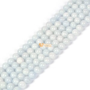 May include: A strand of light blue round gemstone beads. The beads are smooth and polished, and they have a slightly translucent appearance.