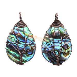 May include: Two abalone shell pendants with a copper wire tree design. The iridescent shells display shades of blue, green, and purple. The wire wraps around the shell, forming a tree shape. The pendants are teardrop-shaped.