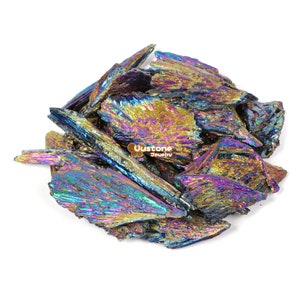 Könnte beinhalten: Ein Haufen irisierender, metallischer, blauer, violetter und goldener Kristalle. Die Kristalle sind scharf und zerklüftet und in einem zufälligen Muster angeordnet. Die Kristalle befinden sich auf einem weißen Hintergrund.