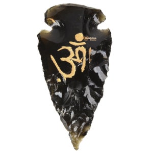 Könnte beinhalten: Schwarzer Obsidian-Pfeilspitzen mit einem goldenen Om-Symbol, das darauf gemalt ist.