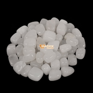 Puede incluir: Un montón de piedras blancas pulidas, también conocidas como cuarzo blanco, para usar en manualidades, fabricación de joyas o decoración del hogar.