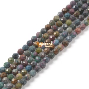 May include: A strand of faceted gemstone beads in shades of blue, green, brown, and purple. The beads are approximately 6mm in diameter and have a slightly irregular shape.