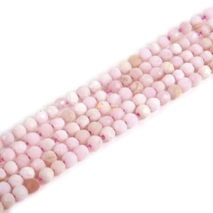 Peut inclure: Un brin de perles d'opale rose, chaque perle est facetée et a une forme légèrement irrégulière. Les perles sont enfilées sur un fil rose fin.