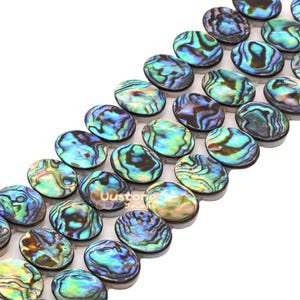 May include: A strand of oval-shaped abalone shell beads featuring iridescent swirls of blue, green, and purple. Each bead displays a unique, polished, and reflective surface with natural patterns. The text Uustone Jewelry is visible on one bead.