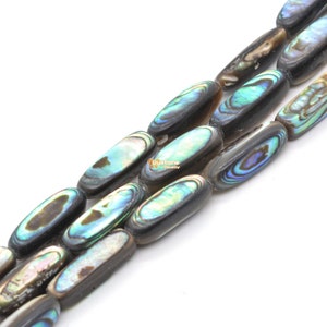 May include: A strand of oval-shaped abalone shell beads with a black backing. The beads have an iridescent blue, green, and gold colour.