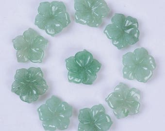 May include: Ten green jade flower-shaped beads, each with five petals, arranged in a circle on a white background.