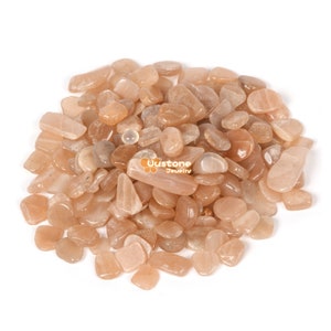 Puede incluir: Un montón de pequeñas piedras de sol pulidas, de color naranja claro. Las piedras son de diferentes formas y tamaños, con un ligero brillo.