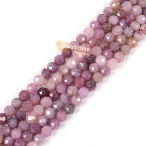 May include: A strand of pink and purple faceted gemstone beads. The beads are round and have a smooth, polished finish.