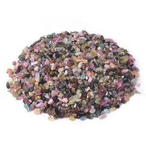 Op de afbeelding: Een hoop kleine, kleurrijke, veelkleurige en iriserende edelsteenchips. De chips zijn een mix van roze, groen, zwart en bruin.